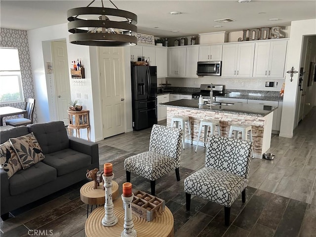 kitchen with white cabinetry, appliances with stainless steel finishes, hardwood / wood-style floors, and pendant lighting