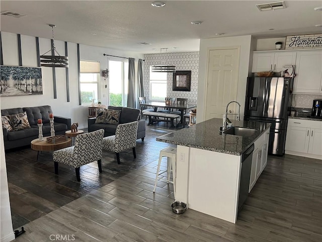 kitchen with a kitchen island with sink, sink, white cabinets, and black refrigerator with ice dispenser