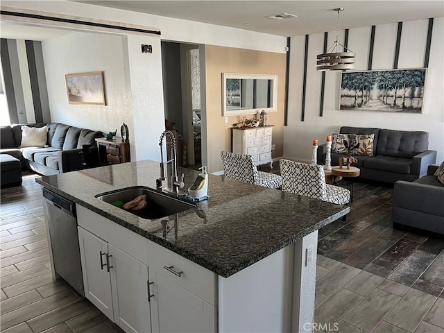 kitchen featuring pendant lighting, sink, white cabinetry, a kitchen island with sink, and stainless steel dishwasher