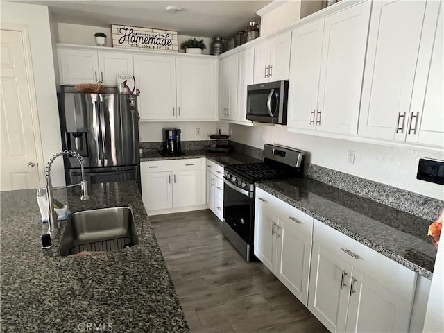 kitchen featuring white cabinetry, sink, dark stone countertops, and appliances with stainless steel finishes