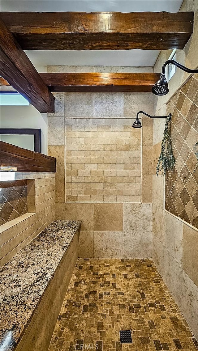 bathroom with tiled shower and beam ceiling