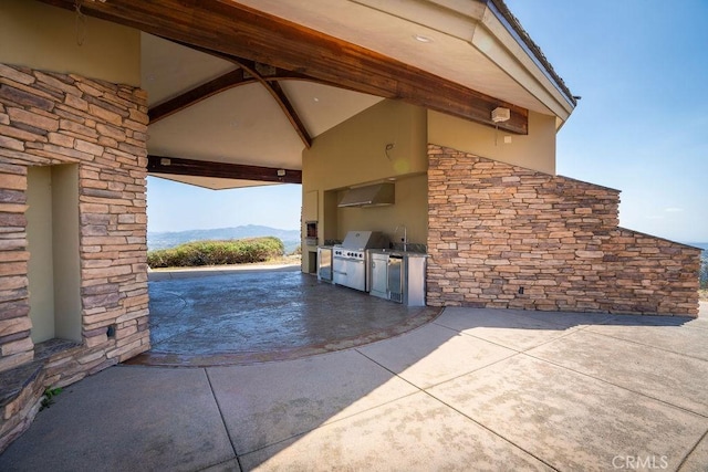 view of patio with exterior kitchen, area for grilling, a mountain view, and sink