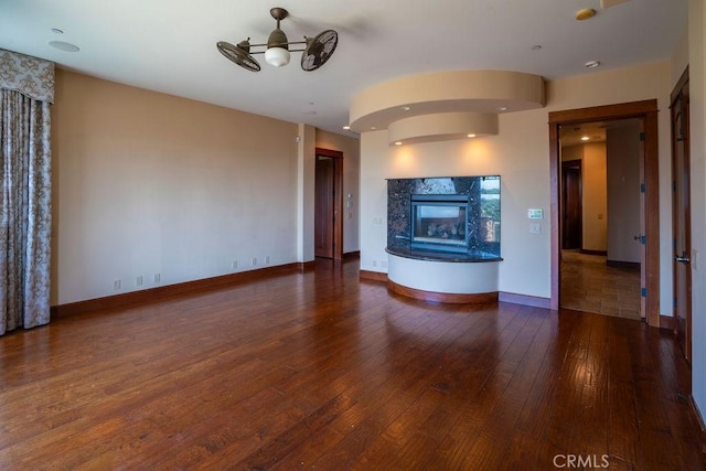 unfurnished living room with ceiling fan, a high end fireplace, and dark hardwood / wood-style floors