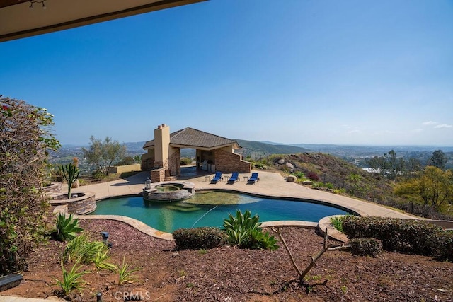 view of pool featuring a mountain view, a patio, and an in ground hot tub