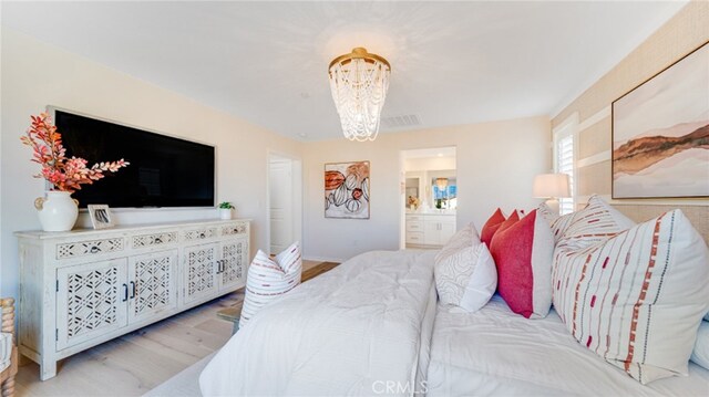 bedroom with an inviting chandelier, connected bathroom, and light hardwood / wood-style floors