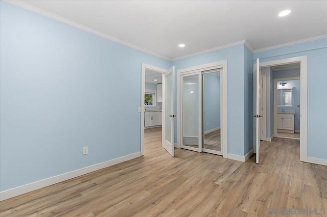 unfurnished bedroom with crown molding, a closet, and light wood-type flooring