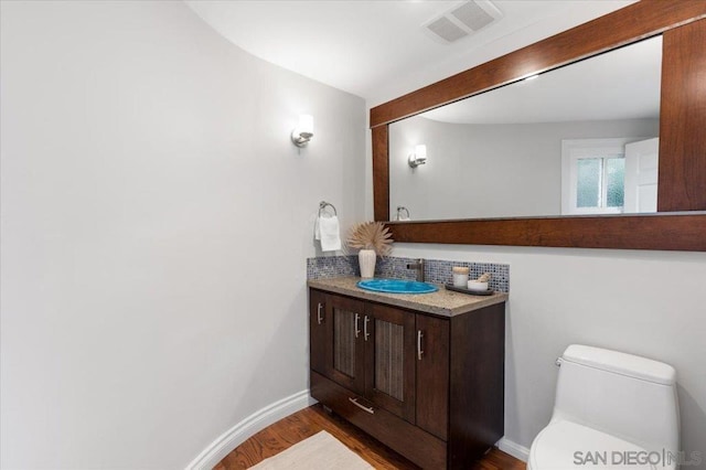 bathroom featuring vanity, toilet, hardwood / wood-style floors, and decorative backsplash