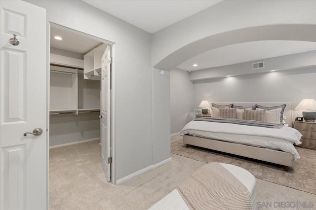 carpeted bedroom with a walk in closet and a closet