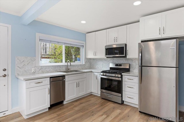 kitchen featuring sink, appliances with stainless steel finishes, backsplash, light hardwood / wood-style floors, and white cabinets