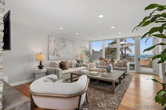 living room featuring a water view, dark wood-type flooring, and a wall of windows