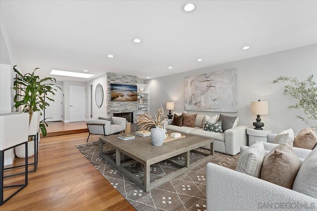 living room with a fireplace, wood-type flooring, and a skylight