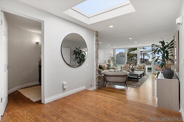 interior space with a skylight, floor to ceiling windows, and light hardwood / wood-style flooring