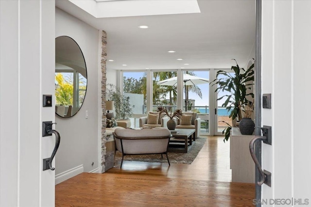 foyer with expansive windows, a water view, a skylight, and hardwood / wood-style floors