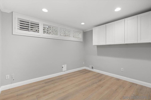 clothes washing area with light hardwood / wood-style flooring and cabinets