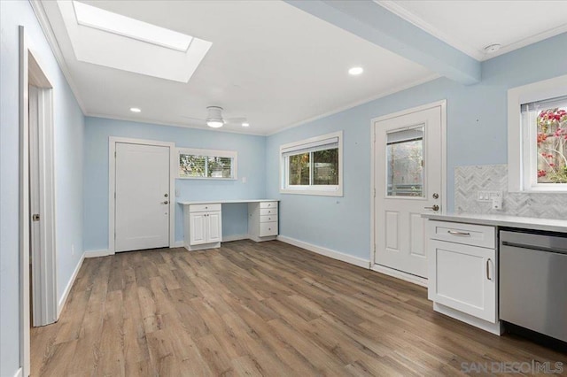 kitchen featuring white cabinetry, crown molding, stainless steel dishwasher, light hardwood / wood-style floors, and backsplash