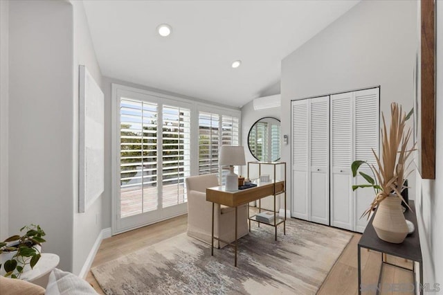 home office with lofted ceiling, light hardwood / wood-style floors, and a wall mounted AC