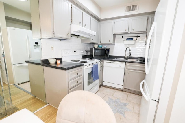 kitchen with tasteful backsplash, sink, white appliances, and light hardwood / wood-style floors