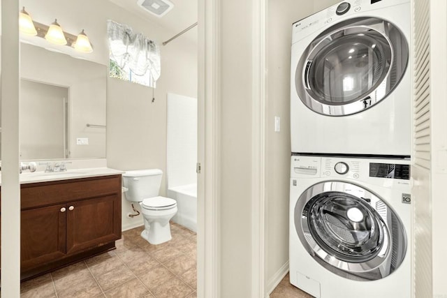 laundry room with stacked washer / dryer, light tile patterned flooring, and sink