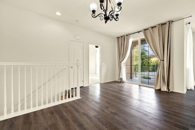 spare room featuring dark hardwood / wood-style flooring and a chandelier