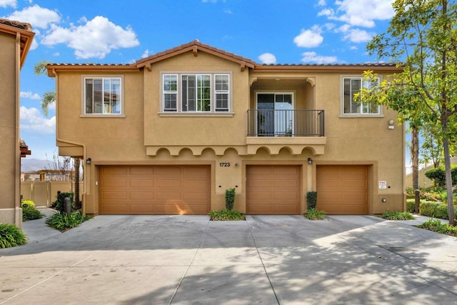 mediterranean / spanish-style home featuring a garage and a balcony