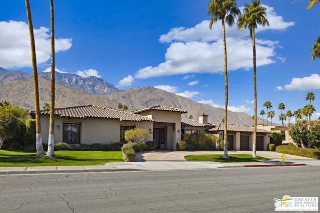 view of front of property featuring a garage, a mountain view, and a front lawn