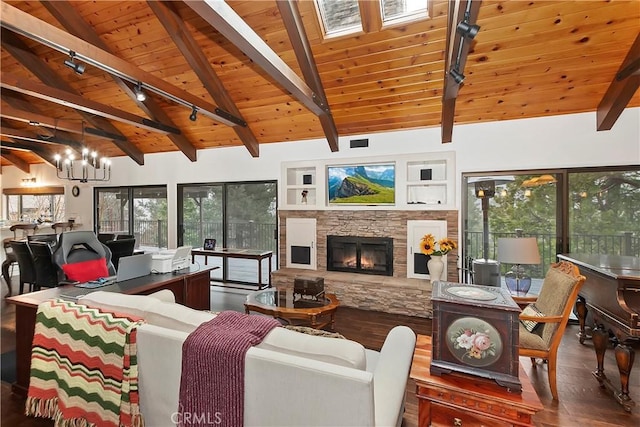 living room featuring a notable chandelier, wood ceiling, a stone fireplace, and vaulted ceiling with skylight