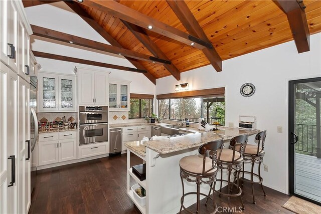 kitchen with a breakfast bar area, white cabinets, decorative backsplash, light stone counters, and kitchen peninsula