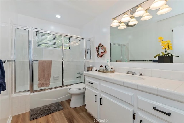 full bathroom featuring toilet, wood-type flooring, shower / bath combination with glass door, and vanity