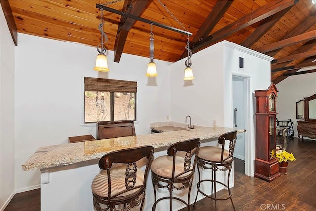 kitchen with pendant lighting, vaulted ceiling with beams, kitchen peninsula, and a kitchen bar