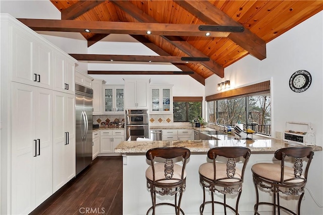 kitchen with sink, white cabinetry, light stone counters, appliances with stainless steel finishes, and decorative backsplash