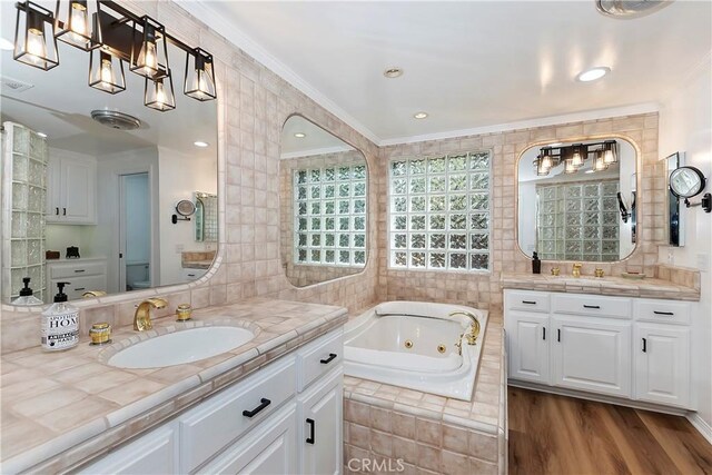 bathroom with tile walls, vanity, a relaxing tiled tub, wood-type flooring, and ornamental molding