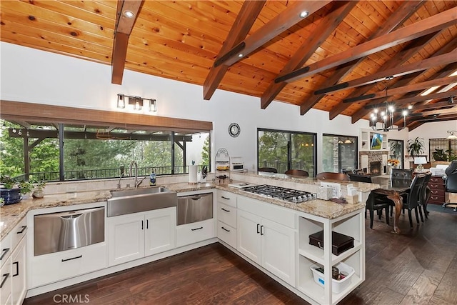 kitchen with sink, white cabinets, light stone counters, and kitchen peninsula