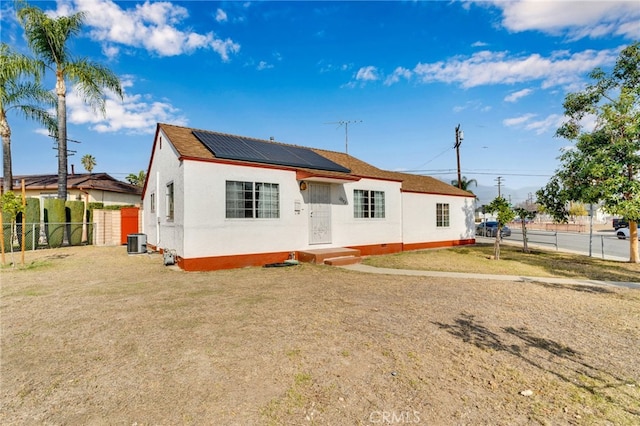 view of front facade featuring cooling unit, a front lawn, and solar panels