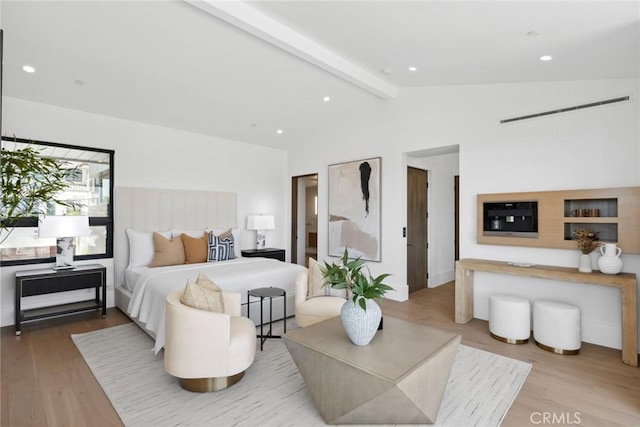 bedroom featuring light hardwood / wood-style floors and vaulted ceiling with beams