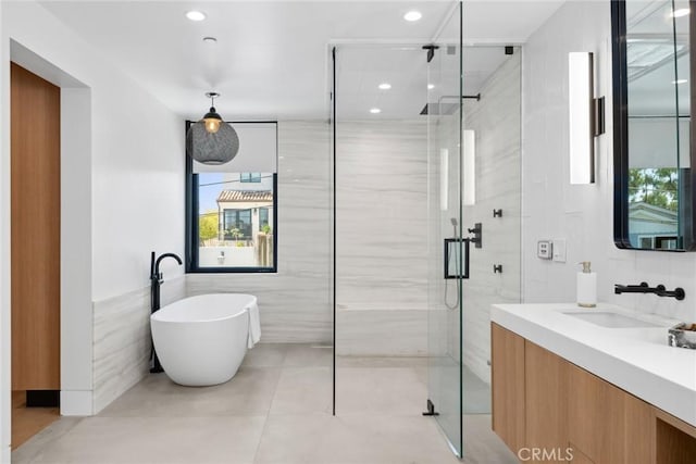 bathroom with vanity, separate shower and tub, and tile walls