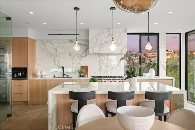 kitchen with sink, tasteful backsplash, black oven, pendant lighting, and light parquet flooring