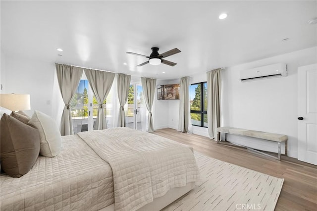 bedroom featuring a wall mounted air conditioner, light wood-type flooring, ceiling fan, and access to exterior