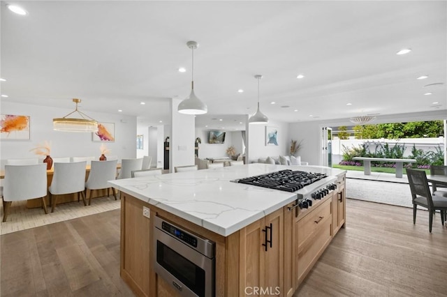 kitchen featuring a large island, decorative light fixtures, light hardwood / wood-style flooring, and stainless steel appliances