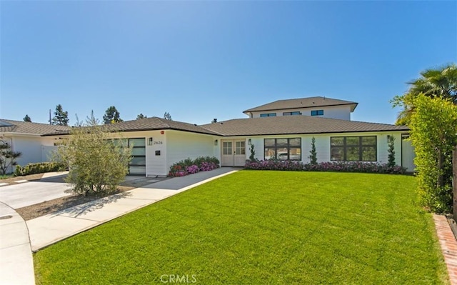 view of front of property with a front yard, french doors, and driveway