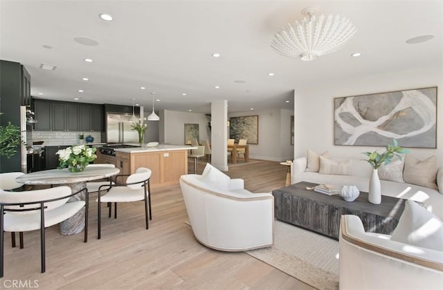 living room featuring light wood finished floors, baseboards, an inviting chandelier, and recessed lighting