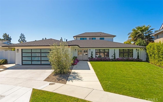 prairie-style house with driveway, french doors, a front yard, a garage, and fence