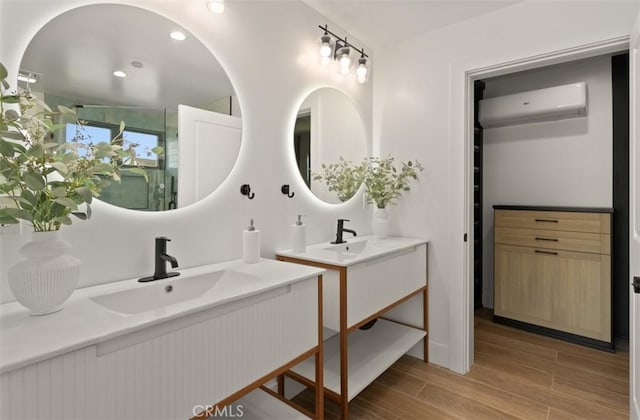 bathroom featuring a sink, two vanities, wood finished floors, and a wall unit AC