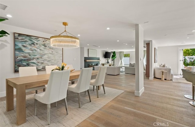 dining room with light wood-style floors, baseboards, a glass covered fireplace, and recessed lighting