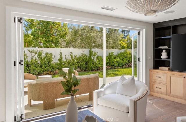 entryway with visible vents, a wealth of natural light, a chandelier, and built in shelves