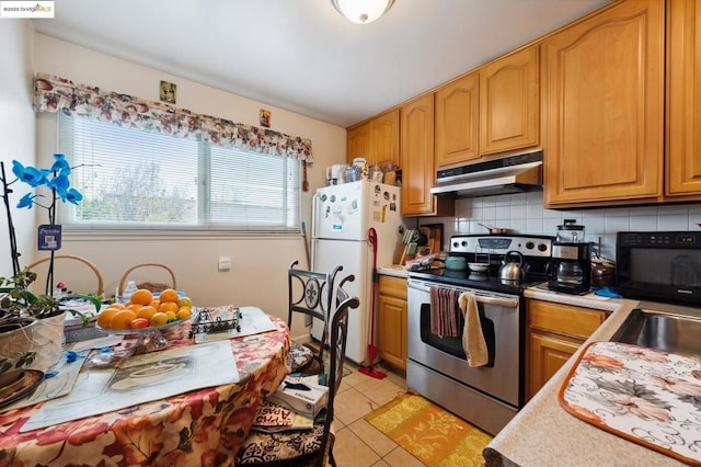 kitchen featuring light tile patterned flooring, sink, stainless steel electric range, white fridge, and backsplash