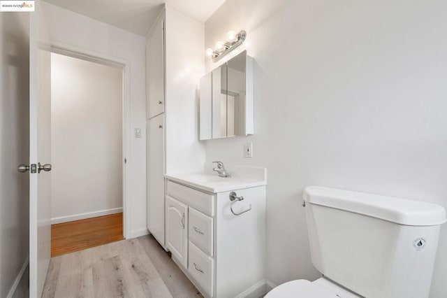 bathroom with vanity, toilet, and hardwood / wood-style floors