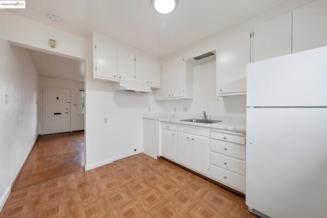 kitchen with white refrigerator, sink, and white cabinets