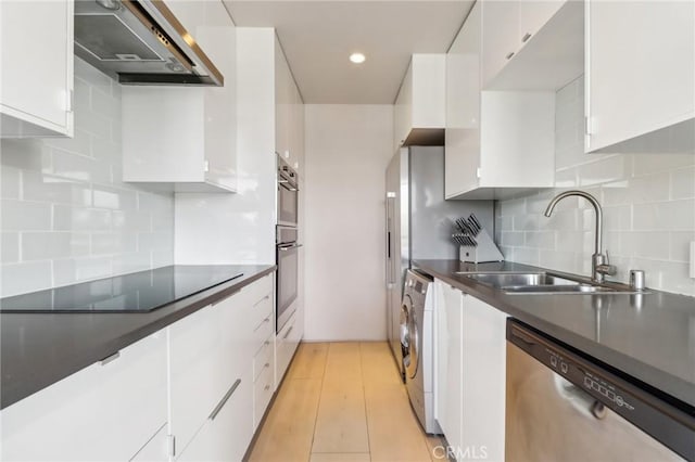 kitchen with white cabinetry, stainless steel appliances, sink, and wall chimney range hood