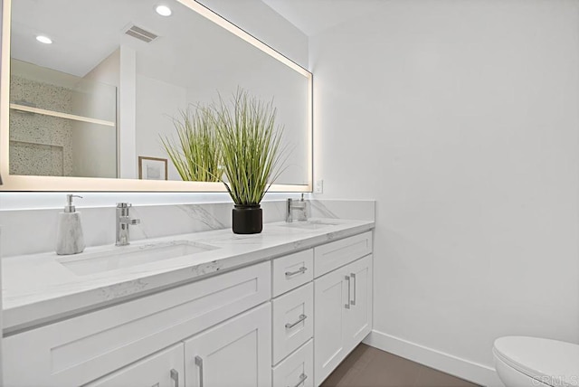 full bathroom with visible vents, a sink, toilet, and double vanity