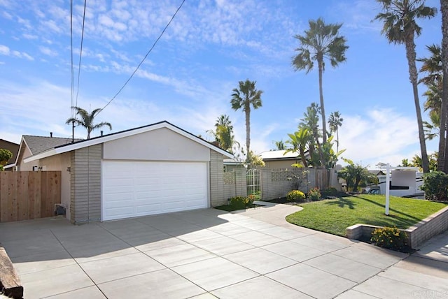 view of front of home featuring a detached garage, fence, a front lawn, and stucco siding